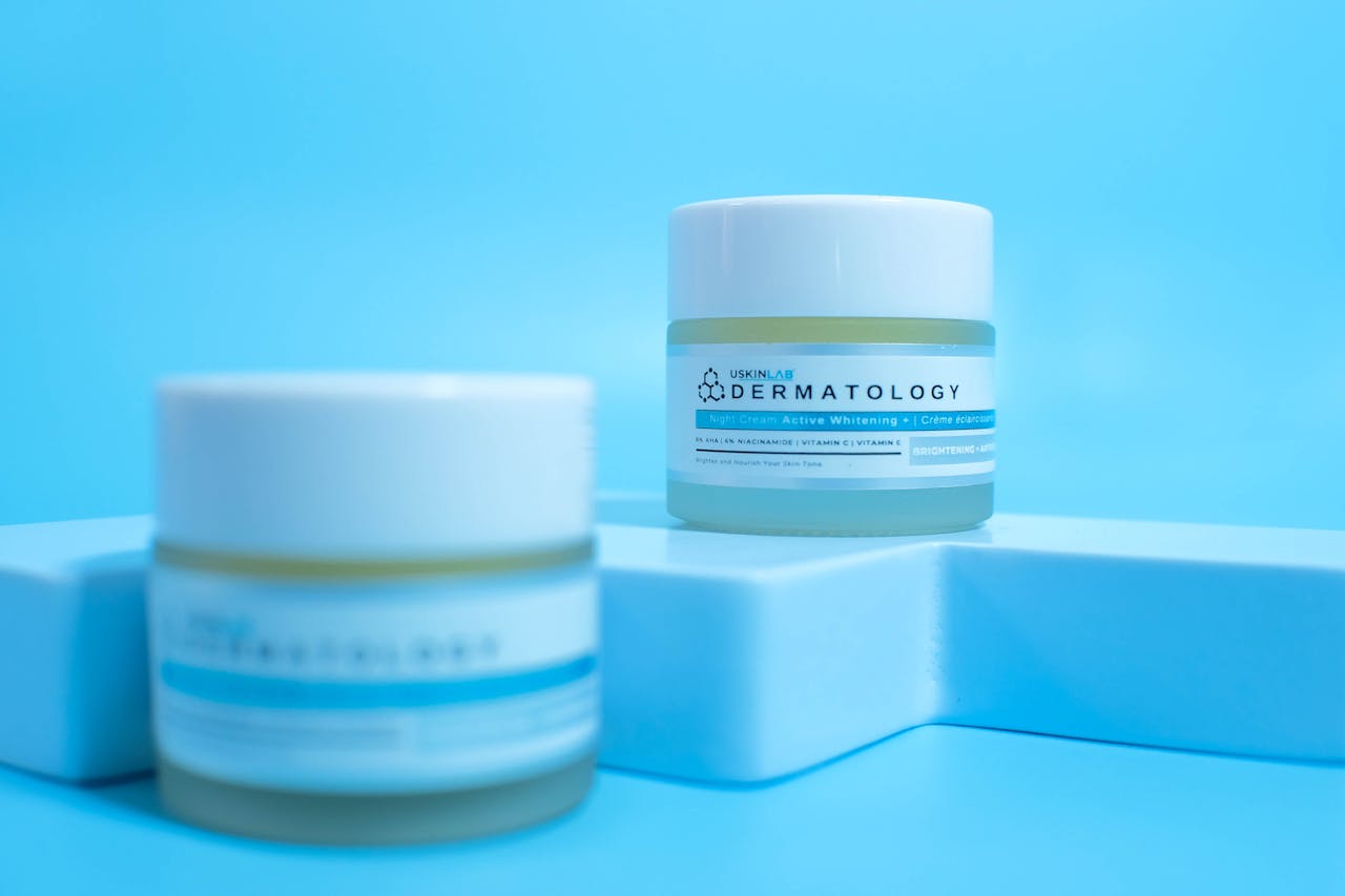 Close-up of skincare cosmetic jars on a modern blue backdrop.